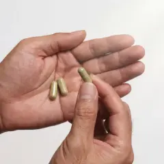 En hand håller tre kapslar, kanske för att behandla testosteronbrist.