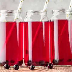 Tre glasflaskor med aroniajuice och sugrör. Perfekt för ett aronia recept.
