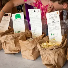 Barn njuter av att poppa popcorn utan fett. De plockar från papperspåsar med olika smaker och berättelser.