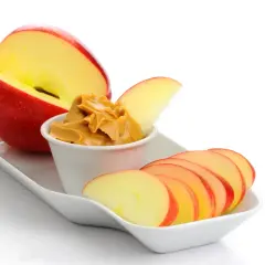 Ett äpple i halvor och skivor med en skål jordnötssmör. Perfekt för lågkalori snacks.