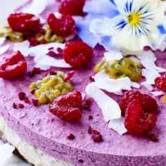 En vacker, lila tårta toppad med hallon, passionsfrukt och kokosflingor. En perfekt idé för nyttiga kakor som ser lika god ut som den smakar.