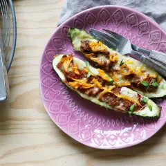 Två ugnsbakade zucchinihalvor fyllda med köttfärs och ost, redo att avnjutas som en del av nyttiga recept.