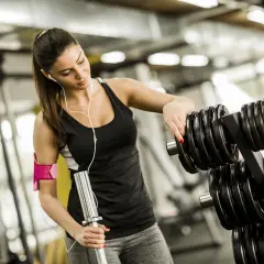 En kvinna väljer vikter på gymmet för sina reps och set.
