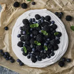 En krämig marängbotten toppad med björnbär och blåbär, garnerad med mynta. En vacker och nyttig dessert.
