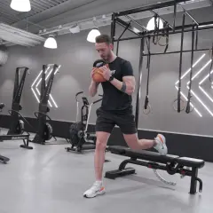 Man gör en utfall med kettlebell i ett modernt gym, perfekt för rumplyft.