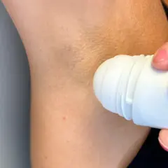 En person applicerar roll-on deodorant under armen. Trots deodoranten kan det ibland lukta svett.