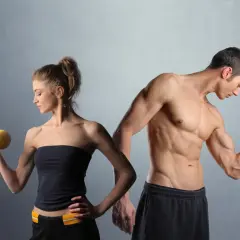 Man och kvinna tränar med hantlar. En muskulös man visar upp sina biceps, en kvinna lyfter en gul hantel. De är i sin anabol fas.