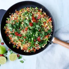 En wok med nyttigt ris, grönsaker, chili och koriander. Serveras med lime.