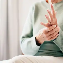 Äldre person som håller sin hand, fingrarna böjda, möjligen på grund av kronisk inflammation.