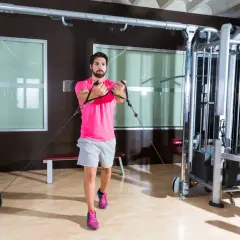 Man tränar bröstmusklerna med cable flyes i ett modernt gym.
