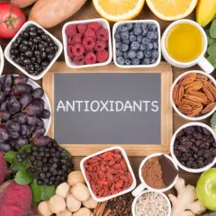 En tavla med texten "ANTIOXIDANTS" omgiven av exempel på antioxidanter som bär, nötter, grönsaker och frukt.