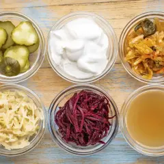 Sex skålar med fermenterad mat: gurka, yoghurt, kimchi, surkål, rödbetor och kombucha.