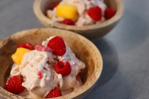 Två skålar med krämig proteinglass, toppad med hallon och mangobitar. Ett perfekt recept för en hälsosam dessert.