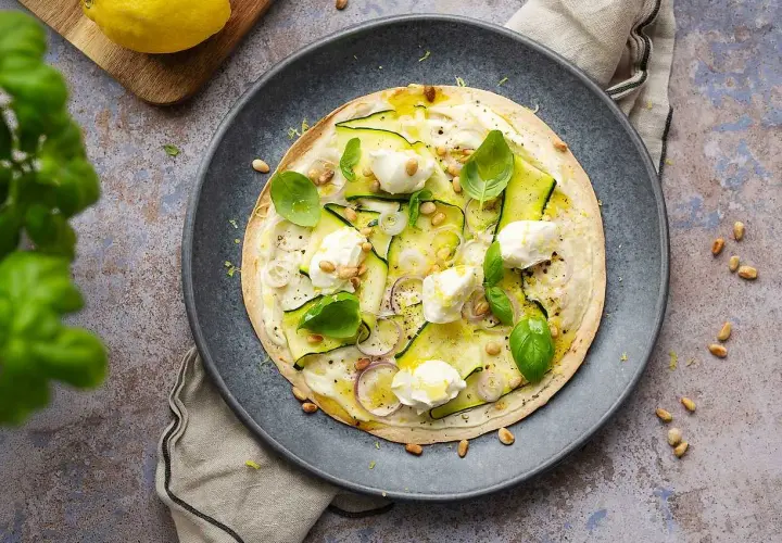 En läcker plattbrödpizza med zucchini, mozzarella och pinjenötter. Perfekt som ett snabbt mellanmål att ta med.