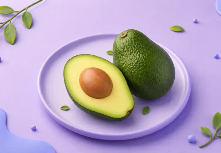 En hel och en halv avokado på en lila tallrik. En grön kvist med blad och lila kulor dekorerar bakgrunden. Avokado kalorier är bra att känna till för en hälsosam kost.