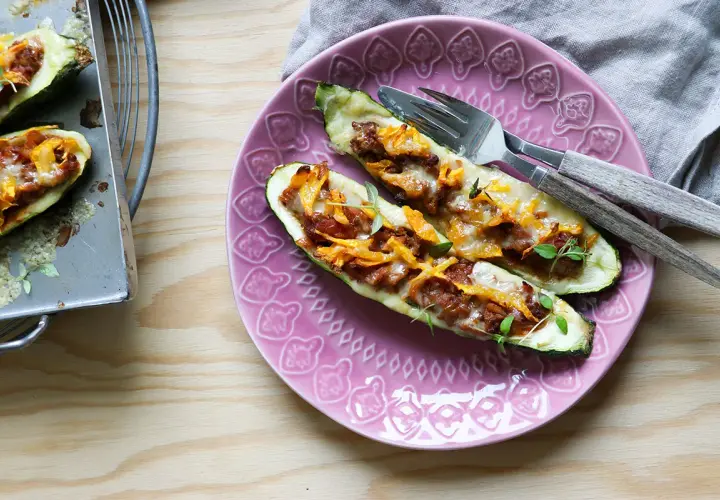 Två ugnsbakade zucchinihalvor fyllda med köttfärs och ost, redo att avnjutas som en del av nyttiga recept.