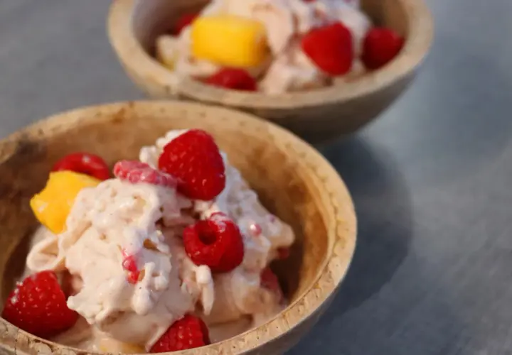 Två skålar med krämig proteinglass, toppad med hallon och mangobitar. Ett perfekt recept för en hälsosam dessert.