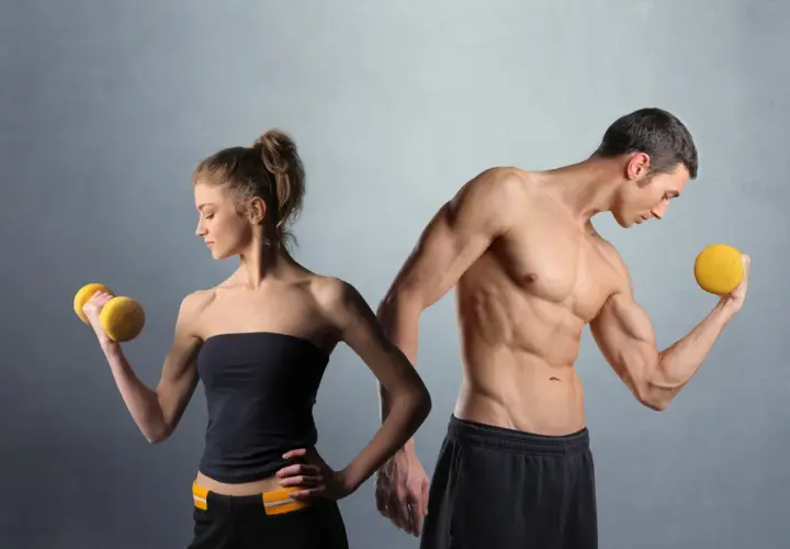Man och kvinna tränar med hantlar. En muskulös man visar upp sina biceps, en kvinna lyfter en gul hantel. De är i sin anabol fas.
