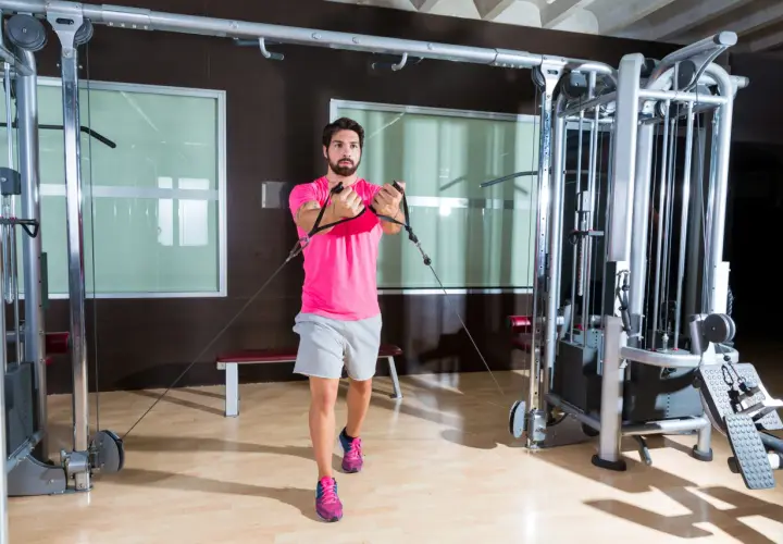 Man tränar bröstmusklerna med cable flyes i ett modernt gym.