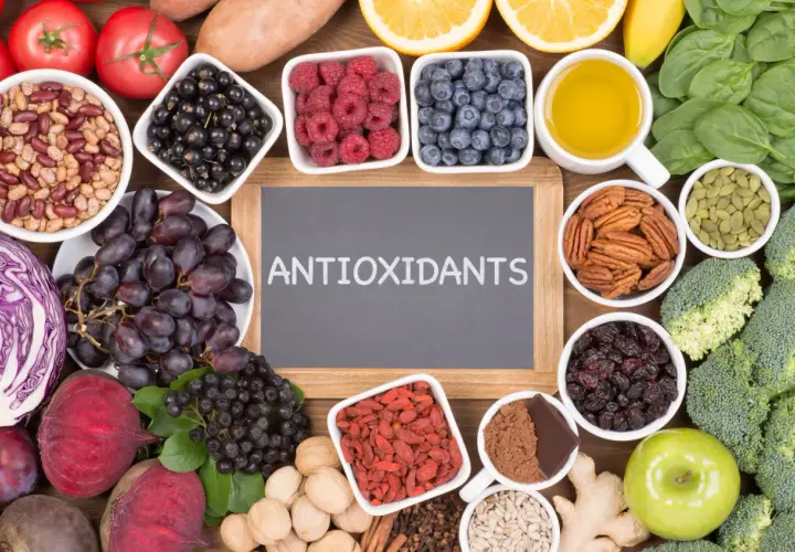 En tavla med texten "ANTIOXIDANTS" omgiven av exempel på antioxidanter som bär, nötter, grönsaker och frukt.