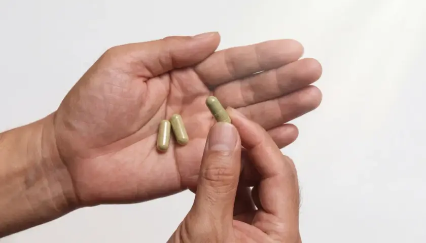 En hand håller tre kapslar, kanske för att behandla testosteronbrist.