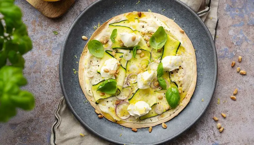 En läcker plattbrödpizza med zucchini, mozzarella och pinjenötter. Perfekt som ett snabbt mellanmål att ta med.