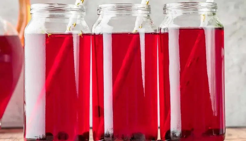 Tre glasflaskor med aroniajuice och sugrör. Perfekt för ett aronia recept.