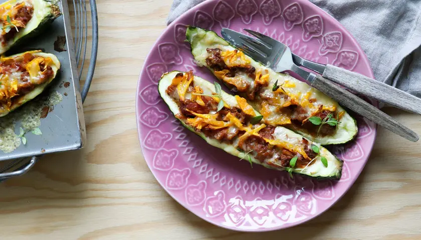 Två ugnsbakade zucchinihalvor fyllda med köttfärs och ost, redo att avnjutas som en del av nyttiga recept.