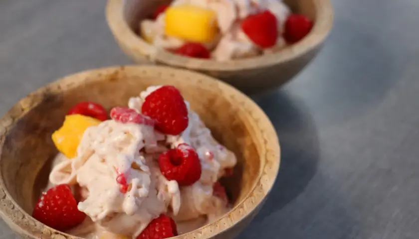 Två skålar med krämig proteinglass, toppad med hallon och mangobitar. Ett perfekt recept för en hälsosam dessert.