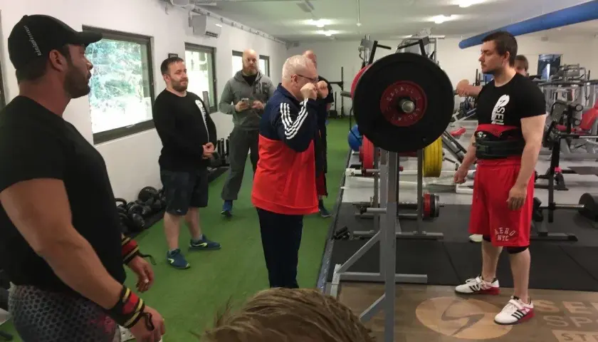 Män i gym klara för styrkelyftsträning. En man förbereder sig för lyft enligt sheiko programmet.
