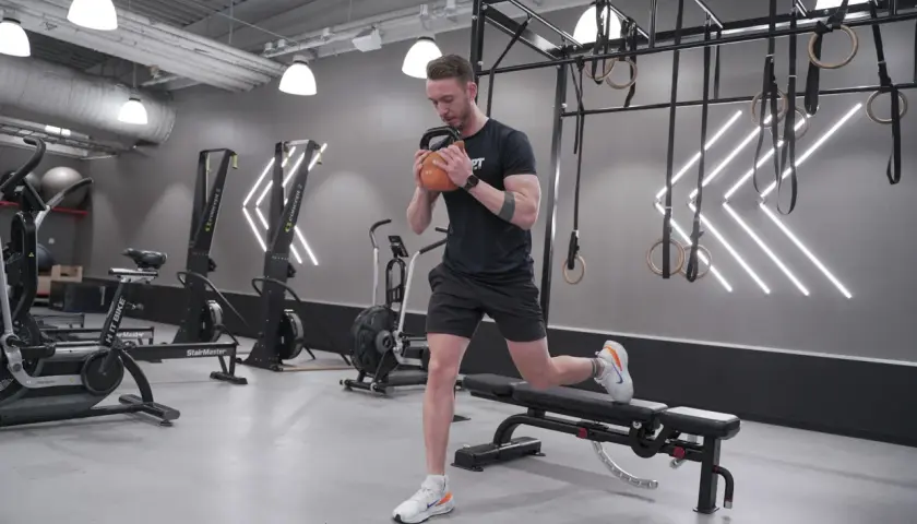 Man gör en utfall med kettlebell i ett modernt gym, perfekt för rumplyft.