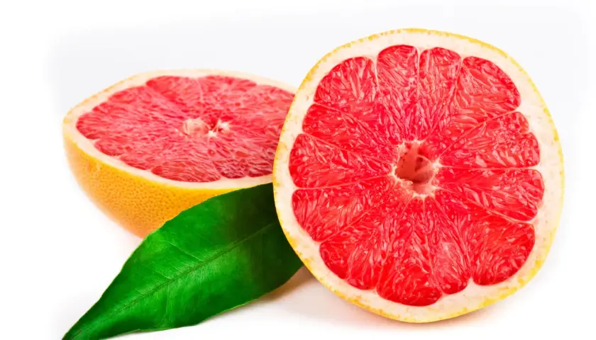 Två halvor av en saftig grapefrukt med en grönskande blad. Grapefrukt kan vara en del av en hälsosam kost för personer med diabetes.
