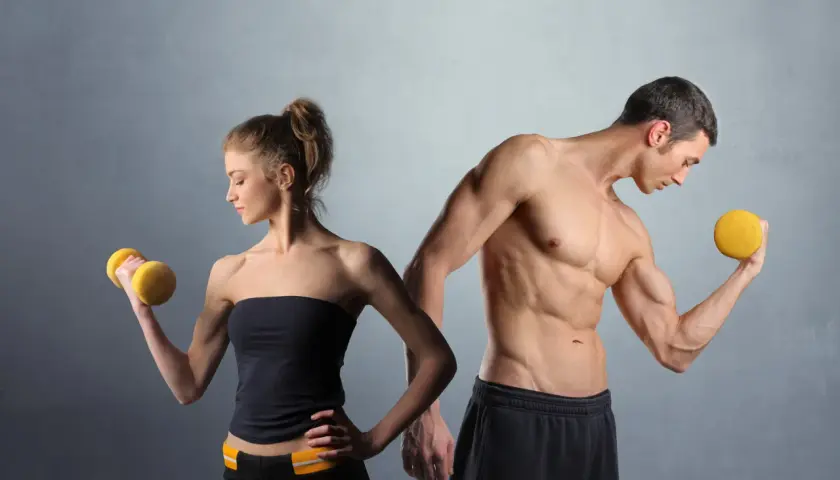 Man och kvinna tränar med hantlar. En muskulös man visar upp sina biceps, en kvinna lyfter en gul hantel. De är i sin anabol fas.