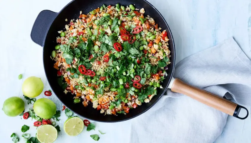 En wok med nyttigt ris, grönsaker, chili och koriander. Serveras med lime.