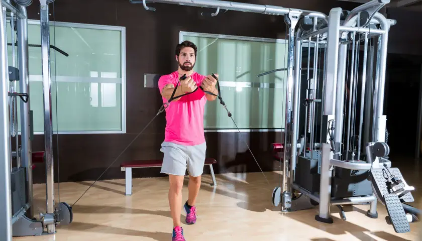 Man tränar bröstmusklerna med cable flyes i ett modernt gym.