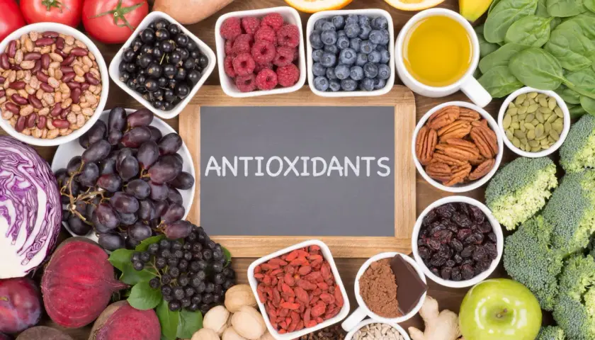 En tavla med texten "ANTIOXIDANTS" omgiven av exempel på antioxidanter som bär, nötter, grönsaker och frukt.