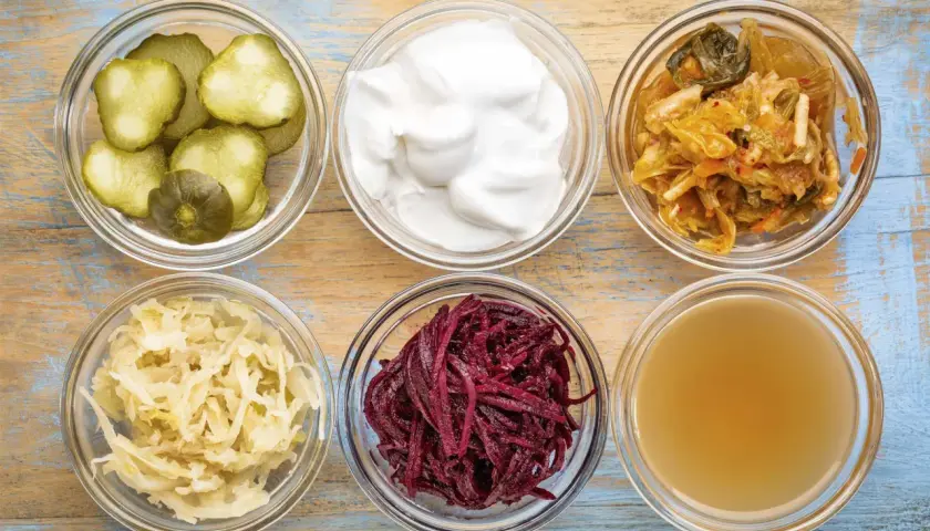 Sex skålar med fermenterad mat: gurka, yoghurt, kimchi, surkål, rödbetor och kombucha.