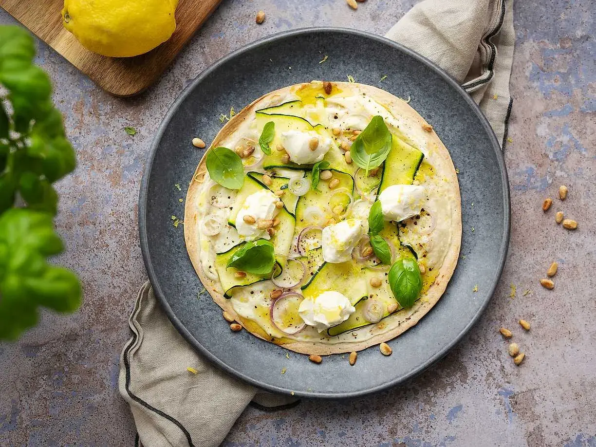 En läcker plattbrödpizza med zucchini, mozzarella och pinjenötter. Perfekt som ett snabbt mellanmål att ta med.