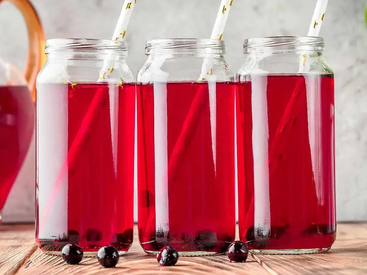Tre glasflaskor med aroniajuice och sugrör. Perfekt för ett aronia recept.