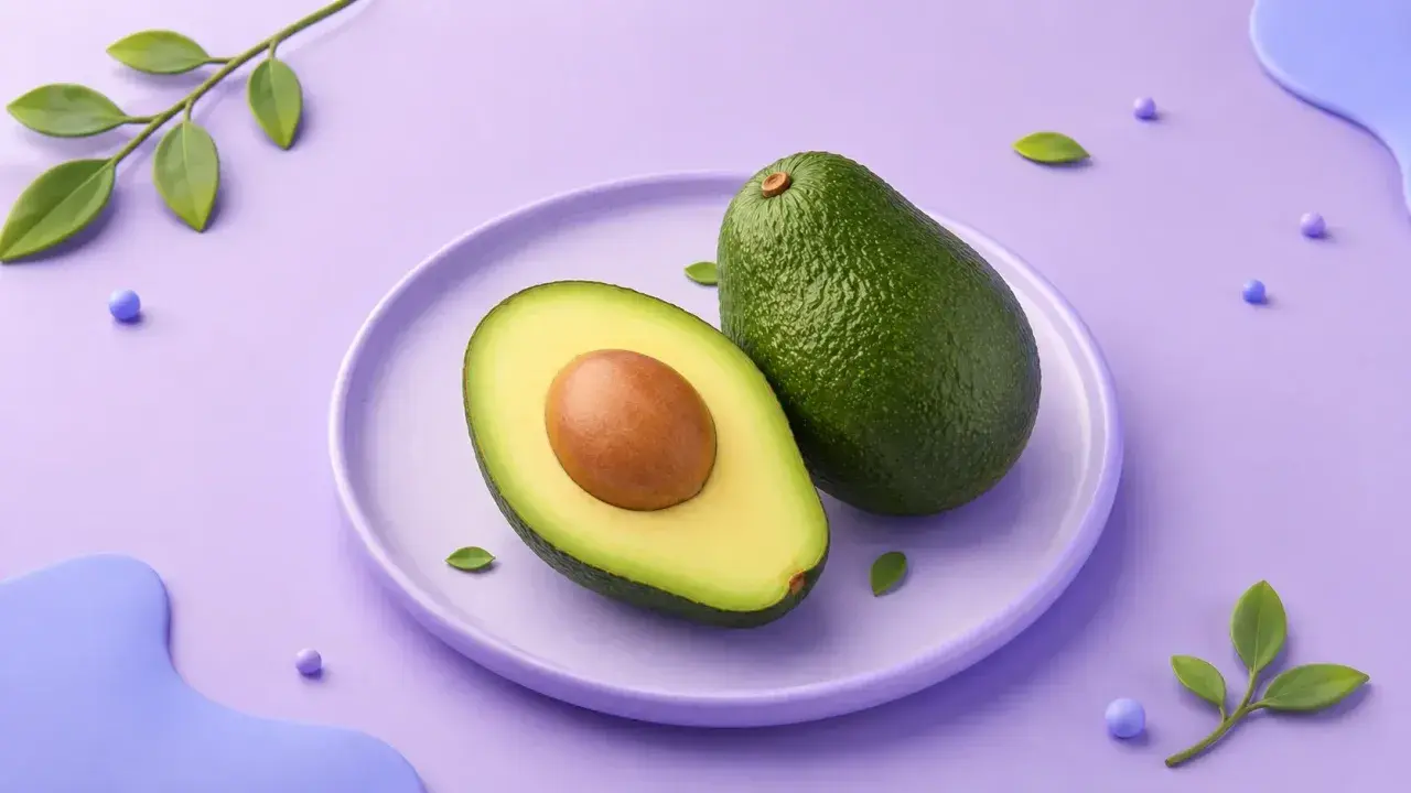 En hel och en halv avokado på en lila tallrik. En grön kvist med blad och lila kulor dekorerar bakgrunden. Avokado kalorier är bra att känna till för en hälsosam kost.