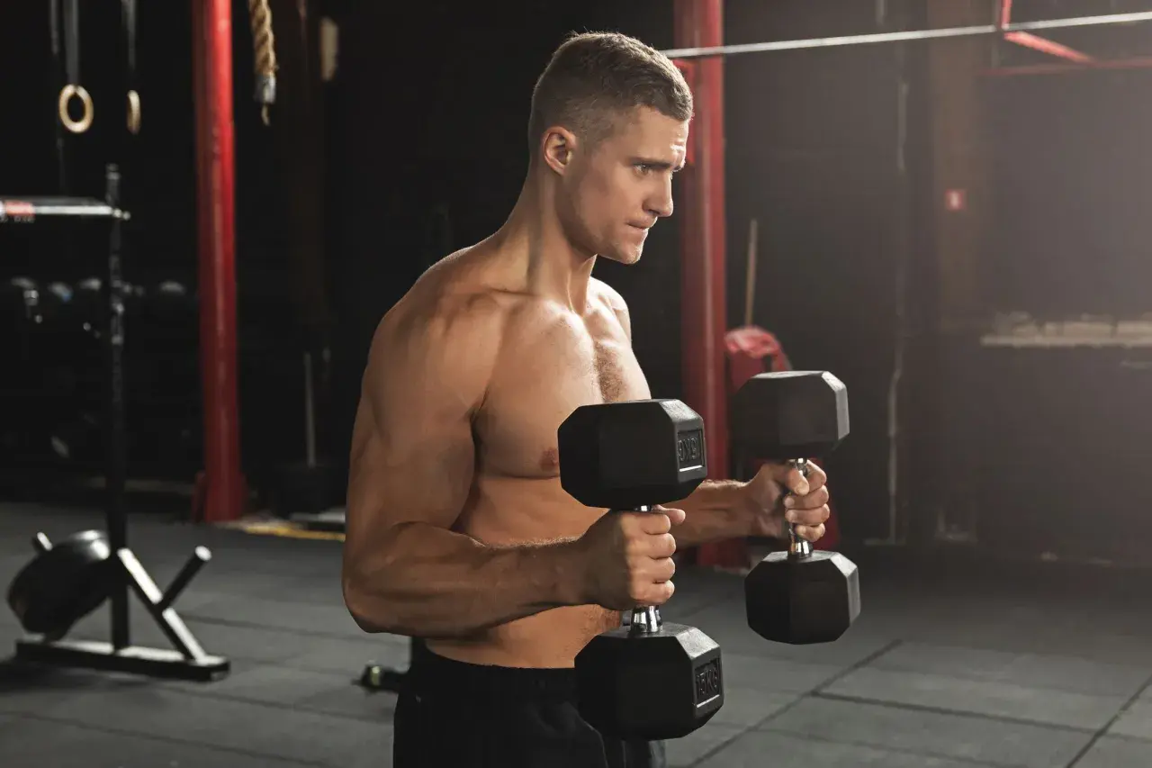 Man utför hammercurls med hantlar i ett gym.