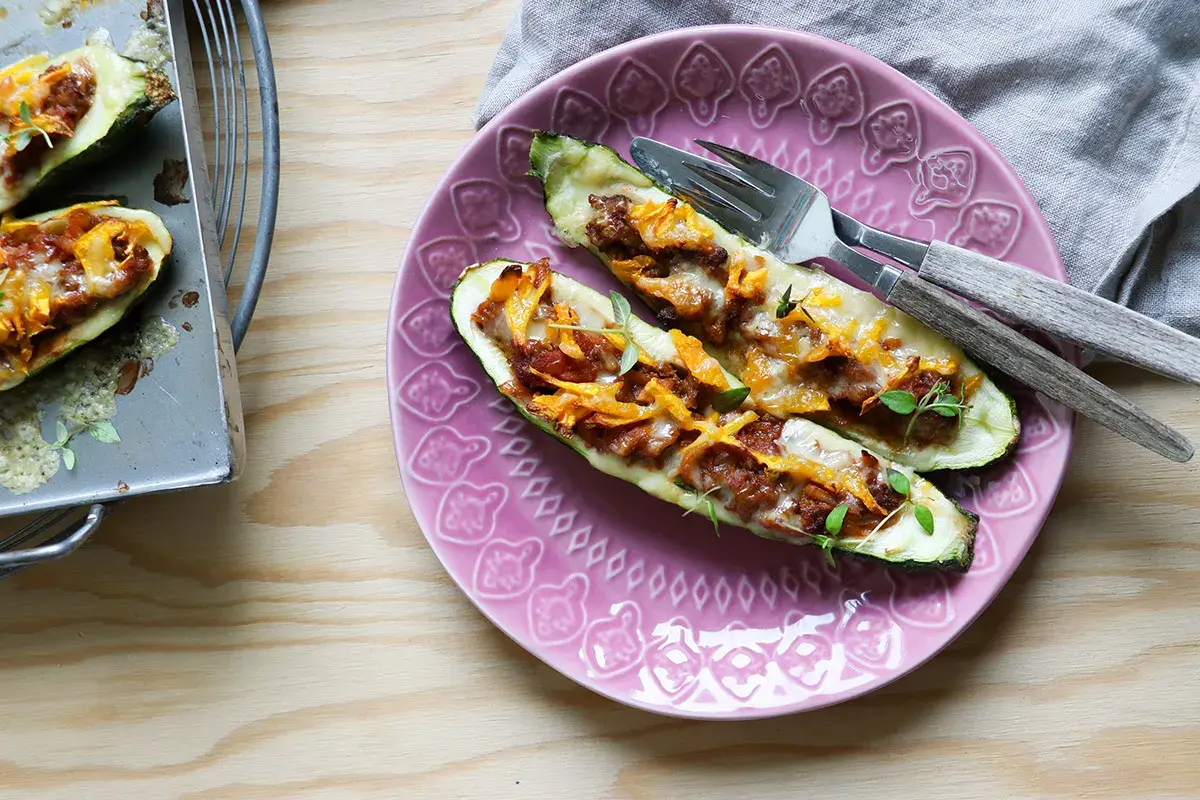 Två ugnsbakade zucchinihalvor fyllda med köttfärs och ost, redo att avnjutas som en del av nyttiga recept.