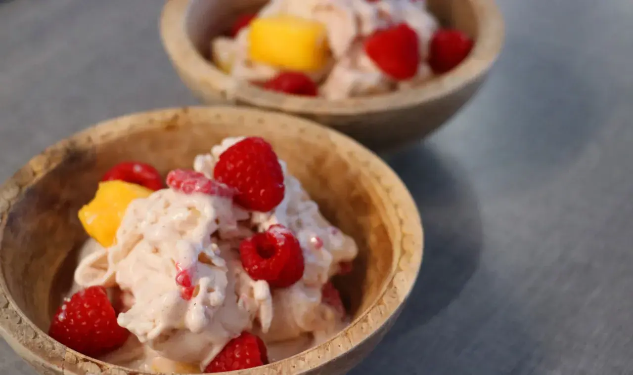 Två skålar med krämig proteinglass, toppad med hallon och mangobitar. Ett perfekt recept för en hälsosam dessert.