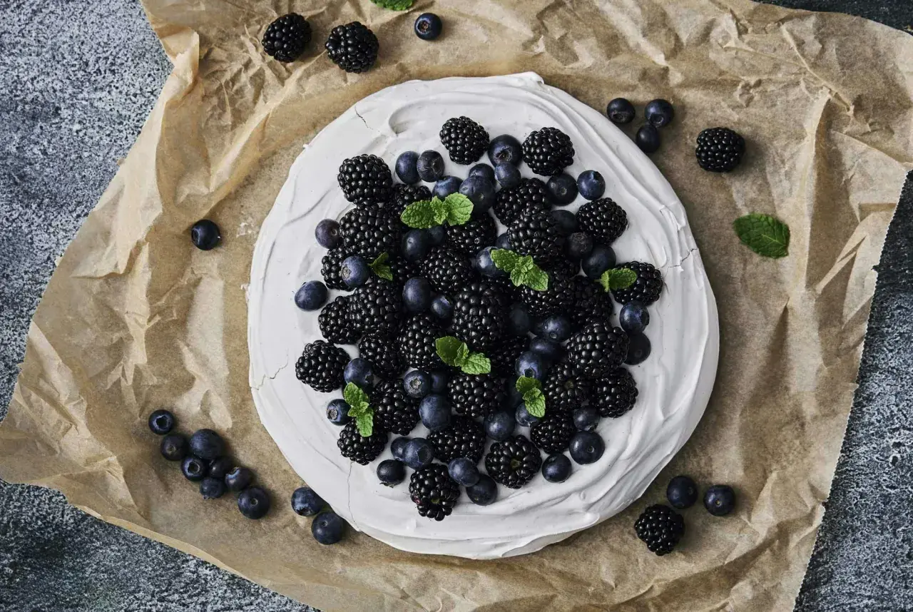 En krämig marängbotten toppad med björnbär och blåbär, garnerad med mynta. En vacker och nyttig dessert.