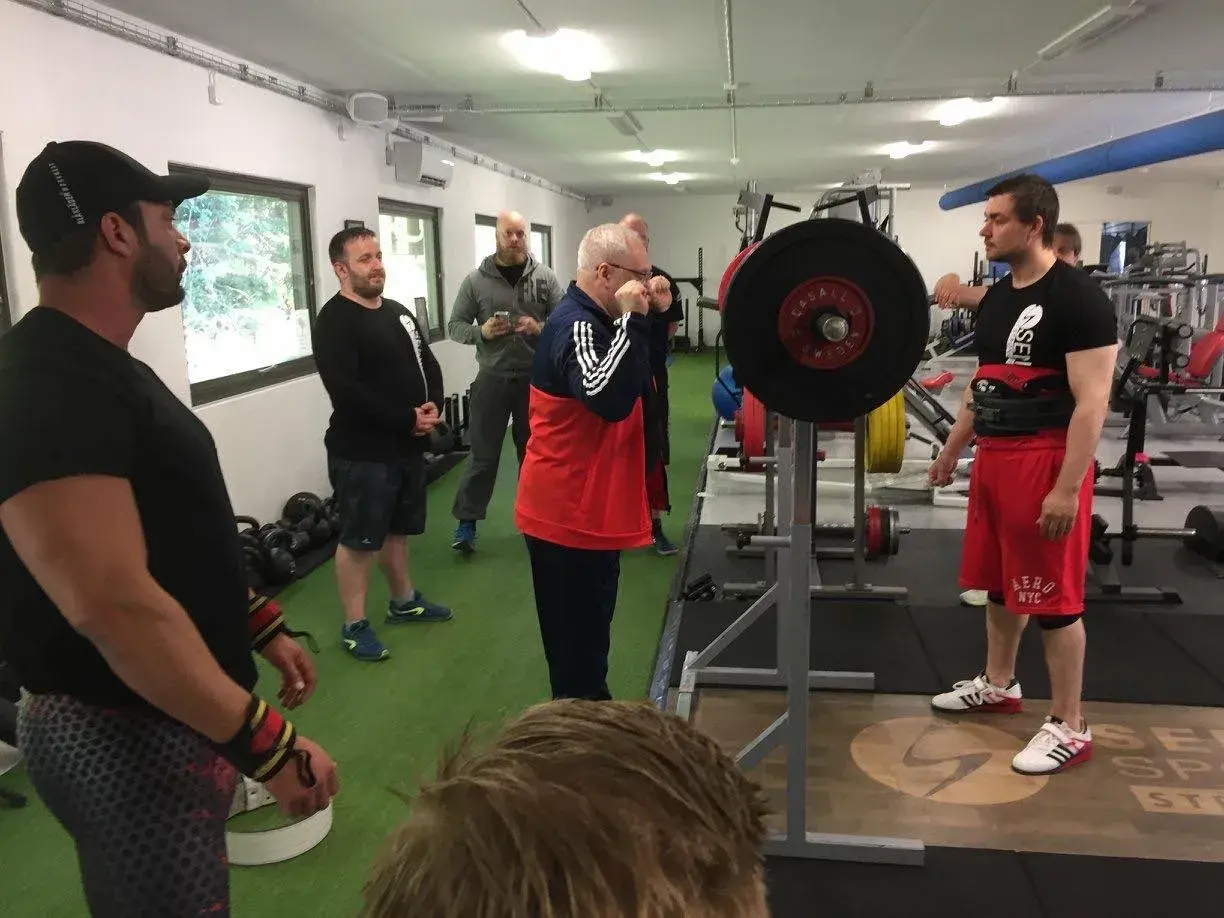 Män i gym klara för styrkelyftsträning. En man förbereder sig för lyft enligt sheiko programmet.
