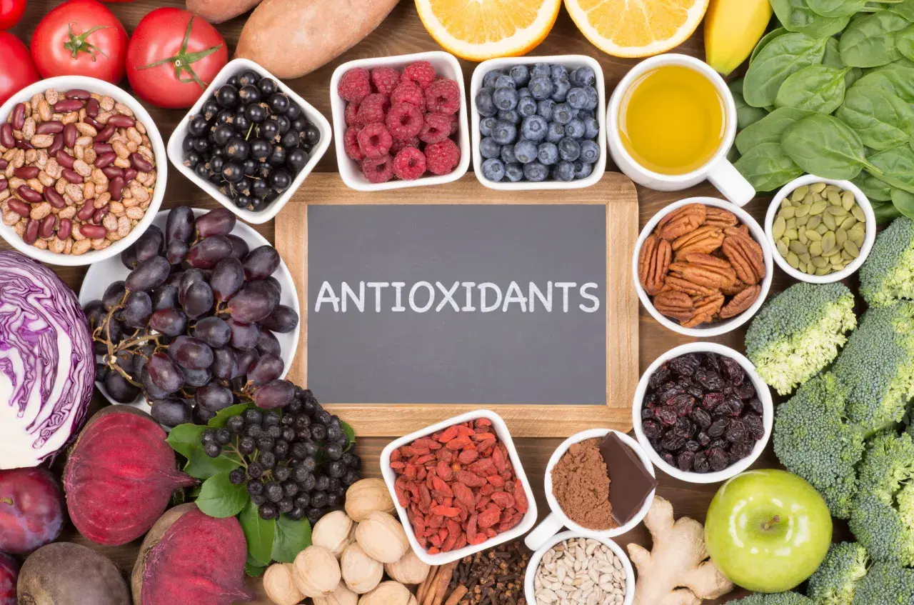En tavla med texten "ANTIOXIDANTS" omgiven av exempel på antioxidanter som bär, nötter, grönsaker och frukt.