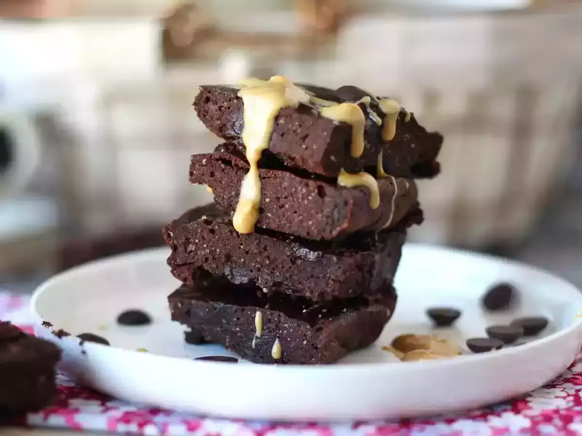 En hög med mörka, saftiga glutenfria godsaker toppade med en krämig sås och chokladknappar.