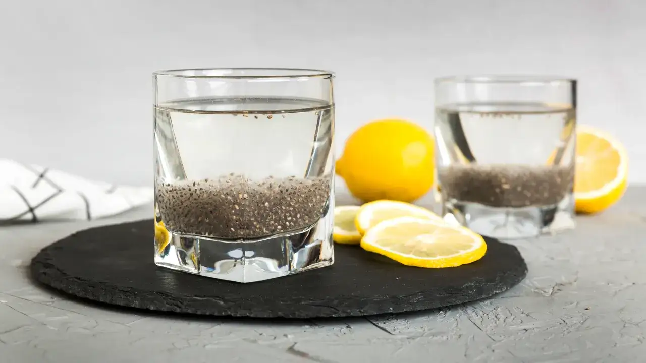 Tv&aring; glas med chia vatten och citronklyftor p&aring; en svart skifferplatta.