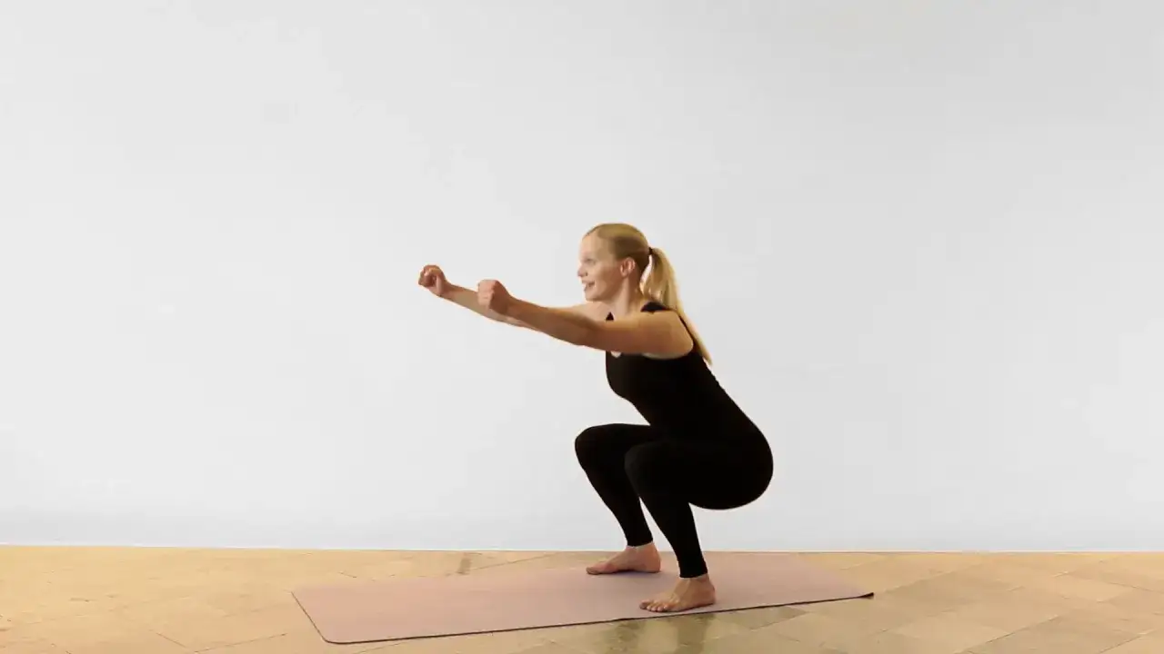 Kvinna utf&ouml;r en sumo squat p&aring; en tr&auml;ningsmatta.