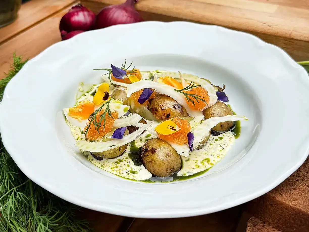 En vacker rätt med små potatisar, fänkål, ägg, rom och blommor. En rätt där potatis kalorier kan vara en del av en balanserad måltid.